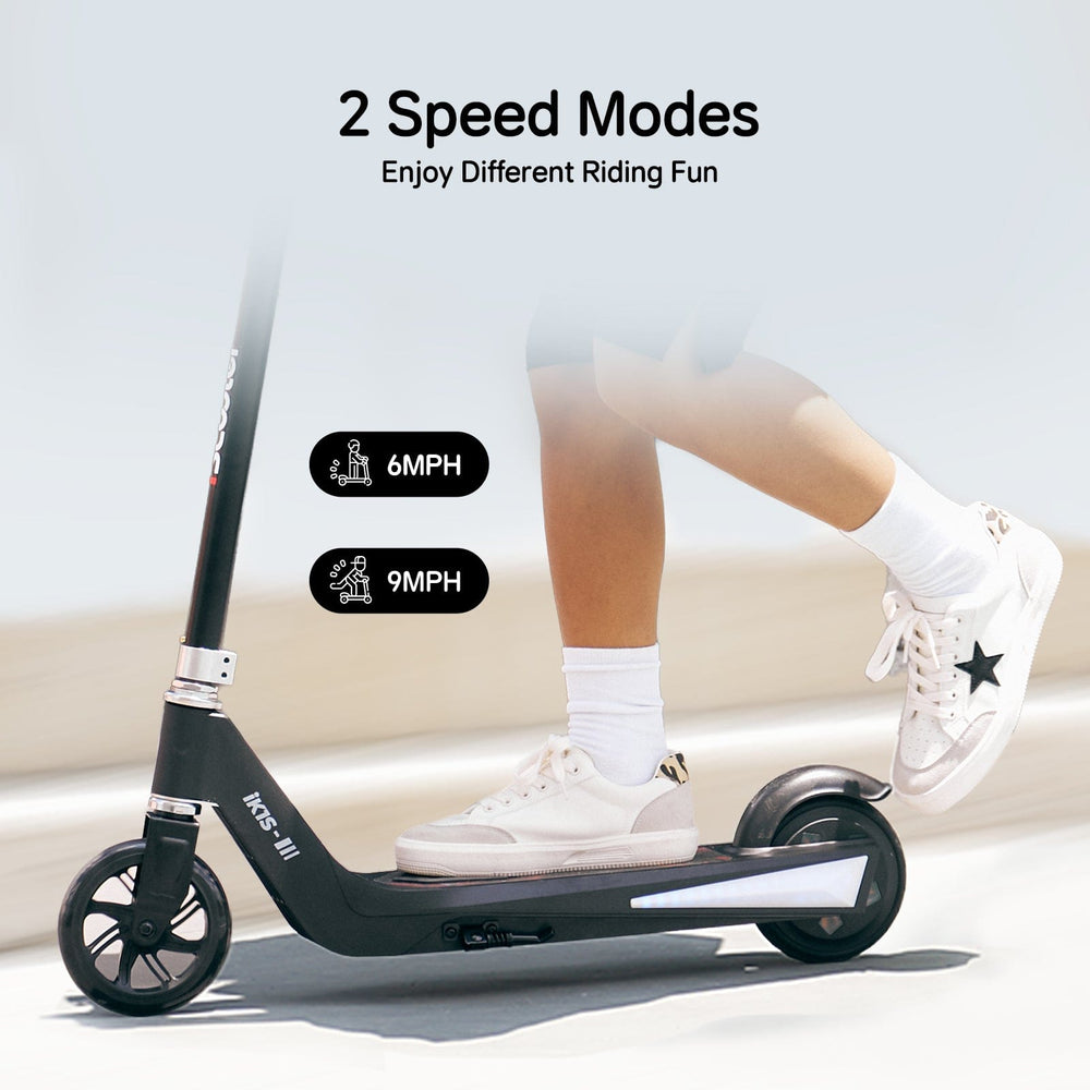 A person rides a sleek black scooter ik1s labeled "KKS-III" on a smooth surface, wearing white sneakers with a star design and white socks. The image highlights two speed modes: 6 MPH and 9 MPH.