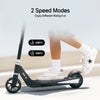 A person rides a sleek black scooter ik1s labeled "KKS-III" on a smooth surface, wearing white sneakers with a star design and white socks. The image highlights two speed modes: 6 MPH and 9 MPH.