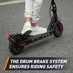A person wearing white sneakers rides a black electric scooter with red accents on a paved road, highlighting its drum brake system for safety.
