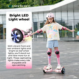A young girl wearing a helmet and protective gear rides a hoverboard H2 with bright LED lights on its wheels, showcasing vibrant patterns. She's balancing confidently on a paved outdoor area, arms outstretched, with a modern building and greenery in the background.