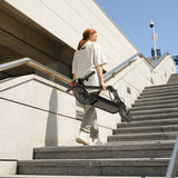 Person carrying a folded electric scooter up a set of stairs.