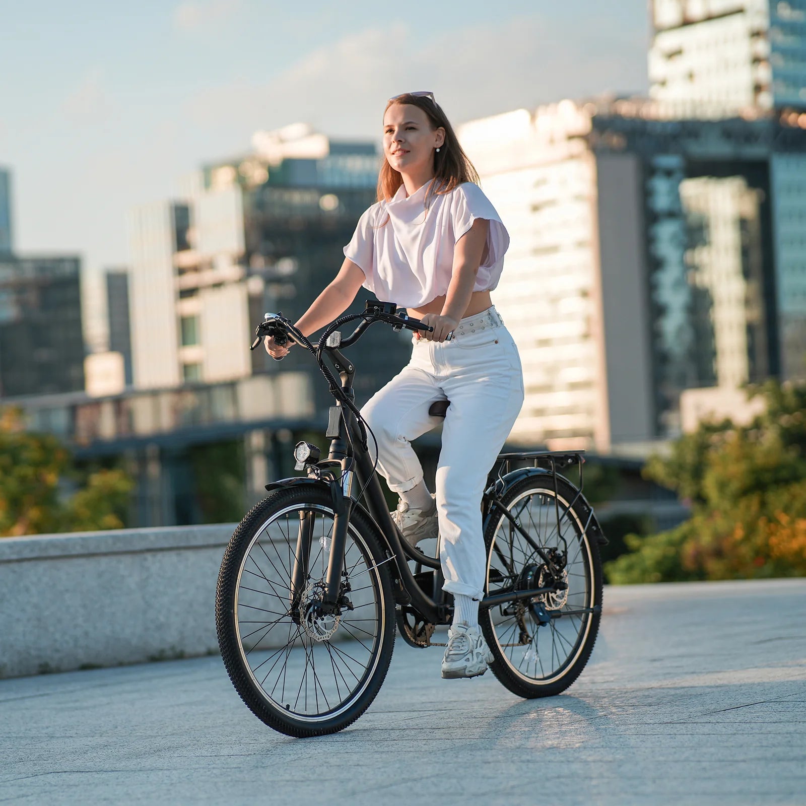 Woman riding a bicycle in an urban setting with modern buildings in the background Woman riding a bicycle in an urban setting with modern buildings in the background