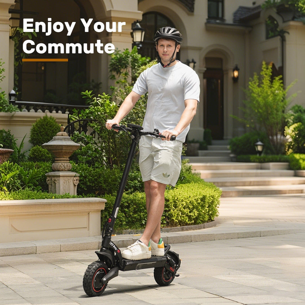 A man wearing a helmet rides an electric scooter ix7pro on a paved path in front of a house with lush greenery and classic architecture, with the words "Enjoy Your Commute" displayed above.