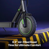 A close-up of an s9pro electric scooter's front wheel with 8.5-inch air-filled tires, featuring sleek black and green accents, positioned on a striped speed bump against a dark background.