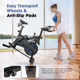 A woman in workout attire is easily moving a stationary bike QK116C with built-in wheels across a sunlit room with large windows overlooking a lake. The bike features blue accents, and the inset images highlight the transport wheels and anti-slip pads for stability.