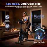A woman wearing headphones exercises on a stationary bike QK116C in a cozy living room, while a dog sleeps on a nearby sofa. The bike features a low-noise belt drive and magnetic resistance, with sound levels under 15dB, ideal for quiet home fitness.