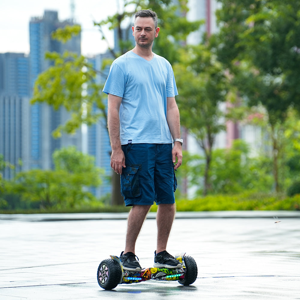 Man standing on a hoverboard with a cityscape and greenery in the background