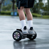 Person riding a hoverboard on a wet pavement with blurred greenery in the background