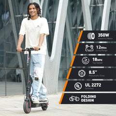 A person rides a sleek black electric scooter with red accents on a paved area near a modern building. The scooter features a 350W motor, 12-mile range, 18 mph top speed, 8.5-inch pneumatic tires, UL 2272 certification, and a folding design.
