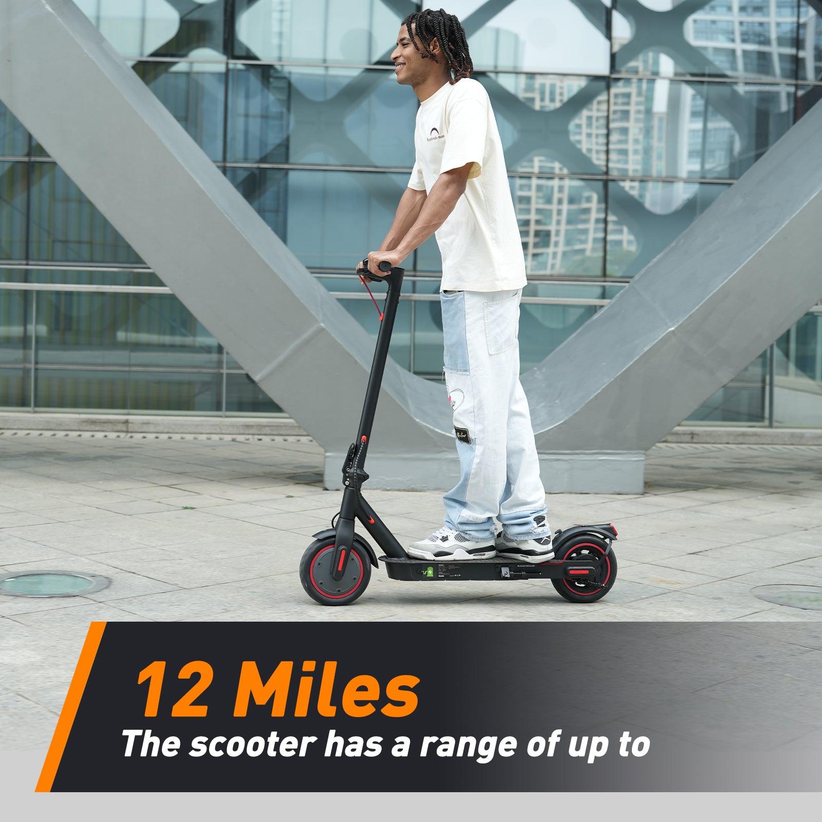 A person rides an electric scooter on a paved urban walkway, with modern architecture in the background. The scooter is black with red accents, and a text overlay highlights its 12-mile range.