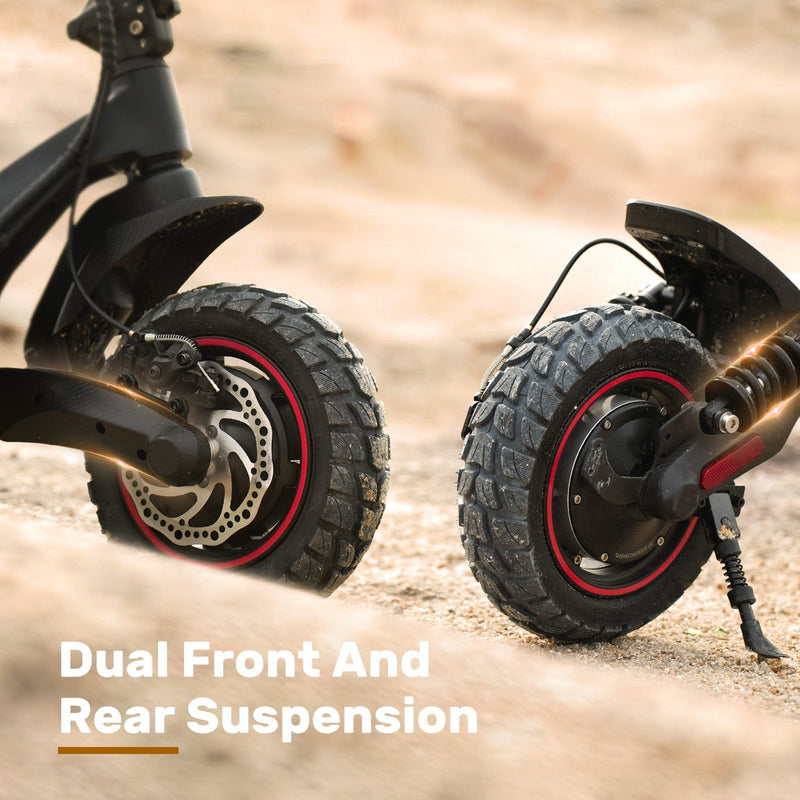 Close-up of a ix7pro scooter's dual front and rear suspension system, showcasing rugged, knobby tires with red rims on a sandy terrain.