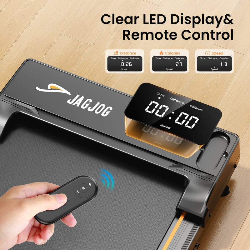 A JAGJOG treadmill JT31 with a sleek black design features a clear LED display showing time, distance, calories, and speed. A hand holds a remote control, emphasizing the device's remote functionality. The treadmill is set on a light wooden floor.