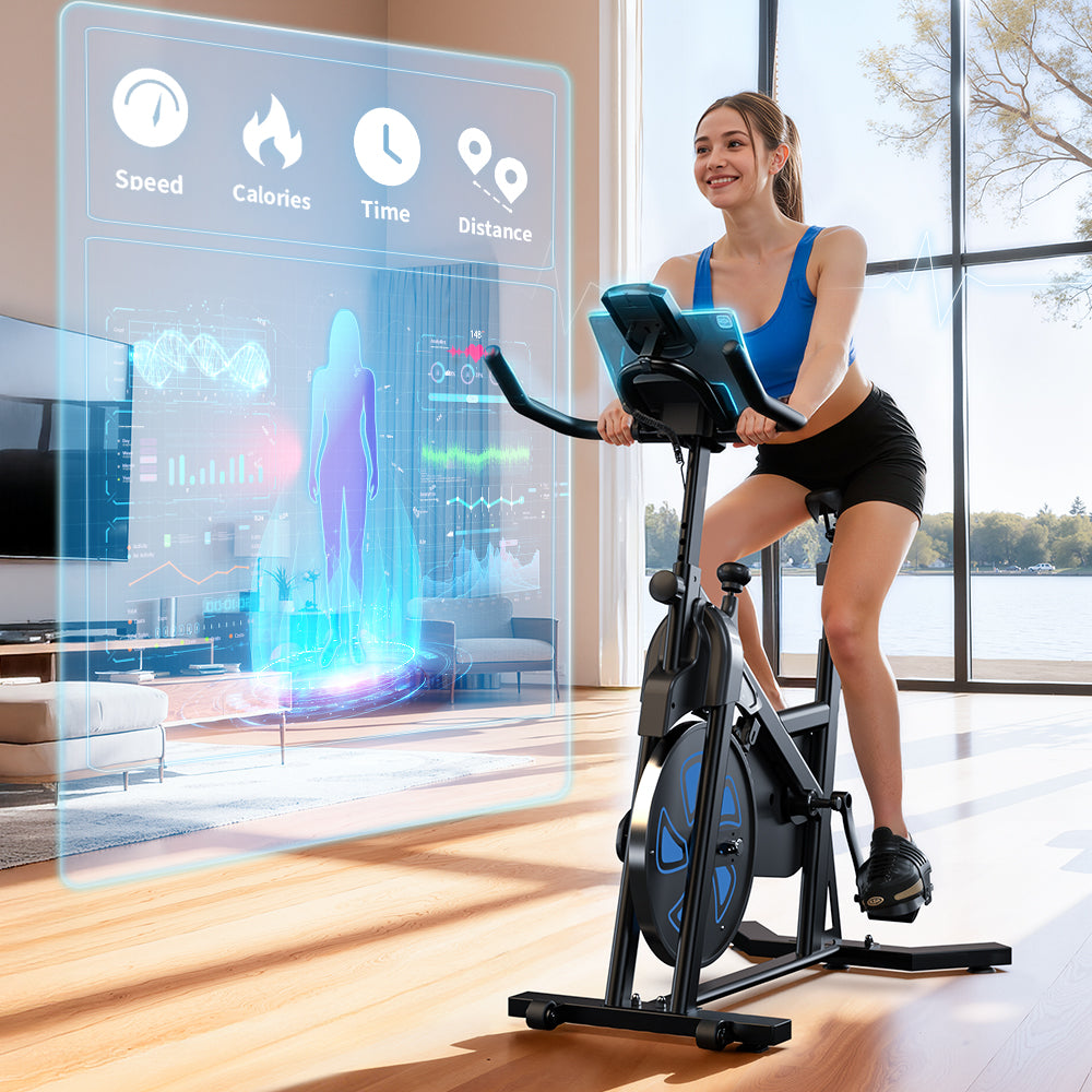 A woman exercises on a stationary bike QK116C in a bright living room with large windows. A futuristic digital display shows metrics like speed, calories, time, and distance. The room has wooden floors and a view of trees outside.